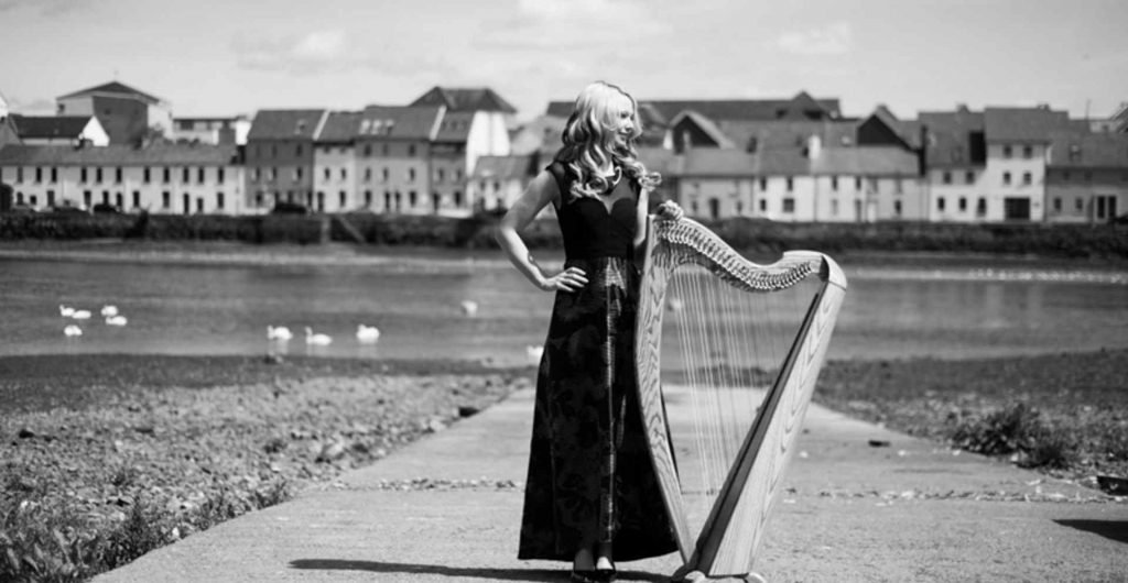 Holly Geraghty with her harp by the Claddagh in Galway